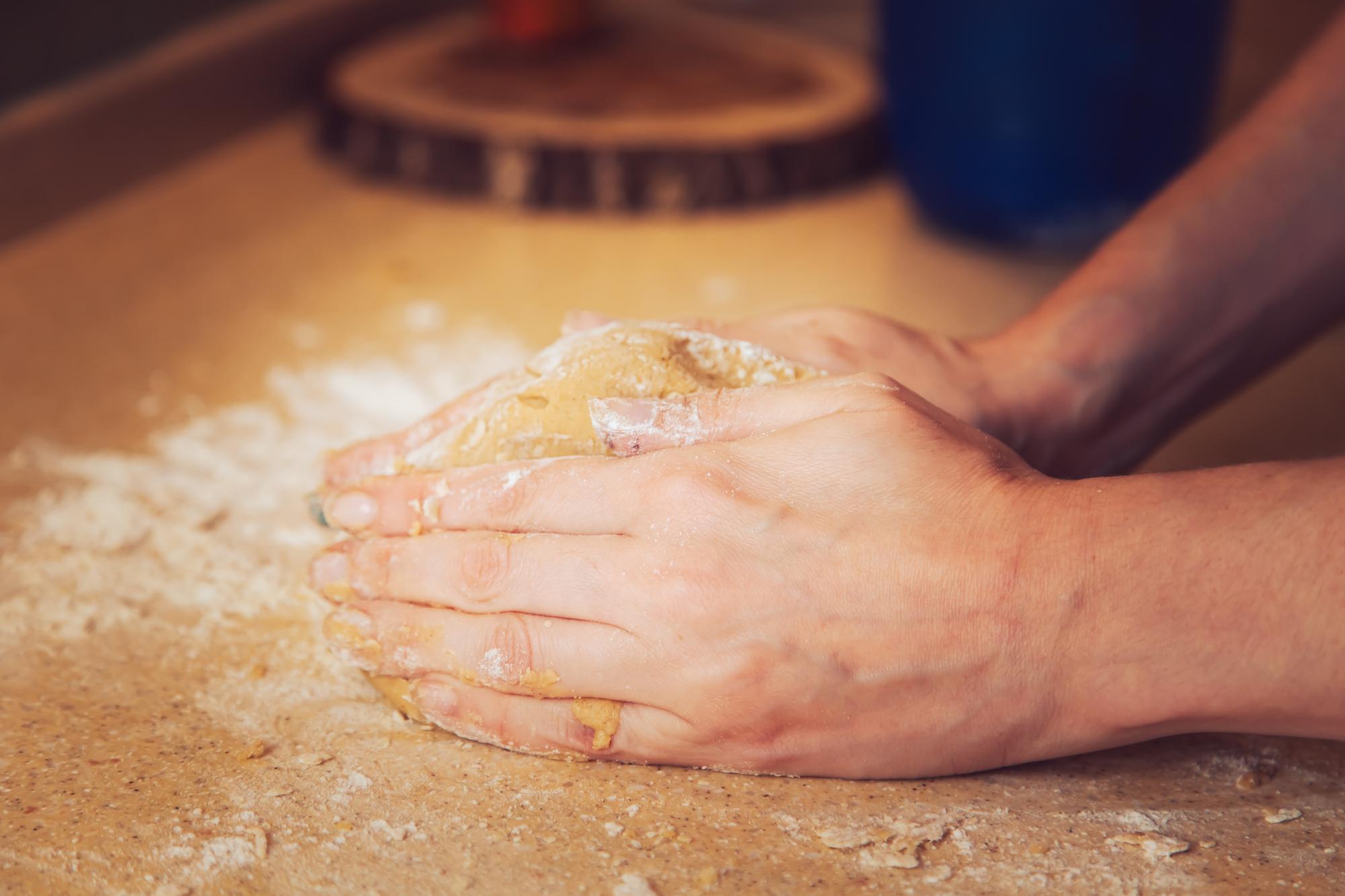 Dettaglio mani che impastano su piano di lavoro